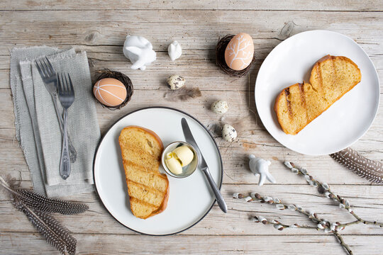 Easter breakfast with golden toasted Easter striezel or also Easter bread with butter with Easter decoration on light wooden background photo taken from above