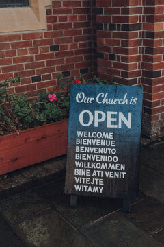 Multilingual Open And Welcome Sign Outside A Church.