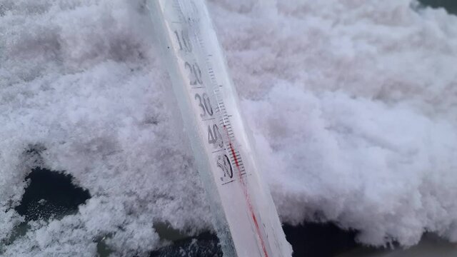 Cold winter thirty-five-degree frost. Thermometer close-up, - 35 degrees celsius below zero. Thermometer on windshield of car. 