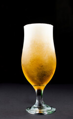glass full of lager style beer, isolated black background