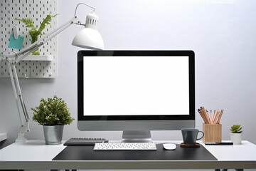 Fototapeta premium Modern workplace with mock up computer, house plant and office suppliers on white desk.