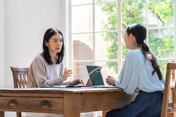 Obraz premium パソコンを使って話す日本人女性二人