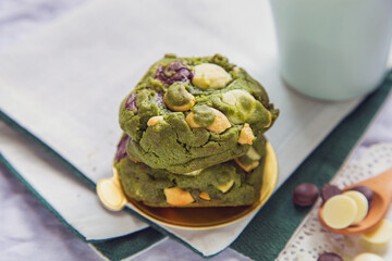 Stack of homemade green tea cookies on a table with a cup of milk background