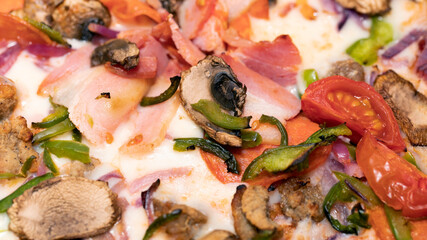 Fototapeta na wymiar pizza with ham, cherry tomatoes, pepper and champignon mushrooms. Close up.