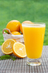 glass of natural orange juice with oranges decorating the background