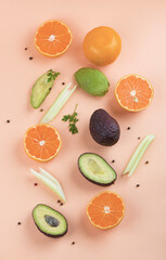 Creative summer pattern made of oranges and celery and avocado on orange background. Fruit minimal concept. Flat lay.