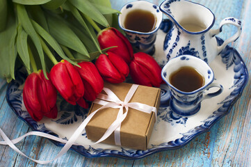 spring still life: a bouquet of red tulips, a tray with two cups of coffee, a box, a milk jug. spring card, 8 March.