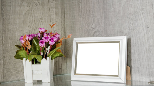 Blank photo frame with white mock up place stands on shelf near flower pot