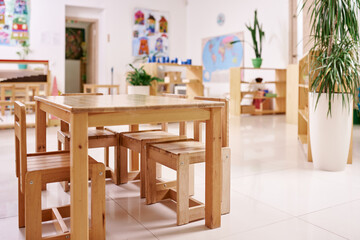 Fototapeta na wymiar Light class in Montessori kindergarten. wooden children's table with chairs in the foreground. nobody