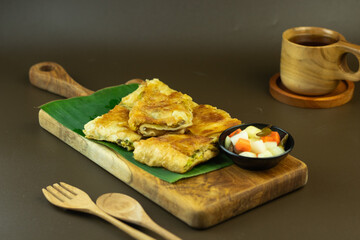 Martabak telur or folded omelette filling with minced meat, spring onion, and egg. Indonesian traditional street food. Isolated brown background, copy space.