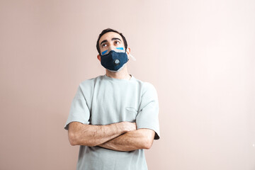 Young middle eastern adult man wearing many face masks. Plain t-shirt. Creative studio shot on nude pastel backdrop. Closeup, space for text