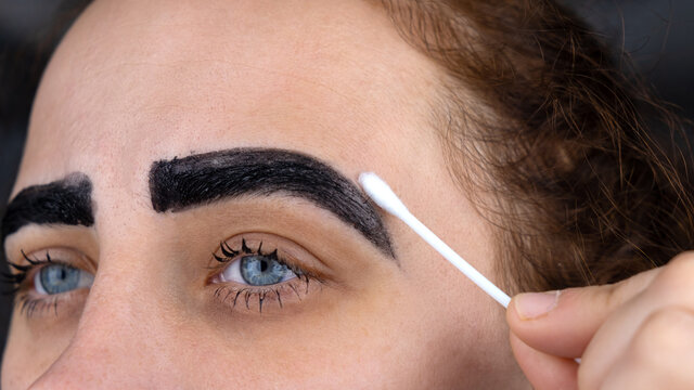 eyebrow dyeing procedure, girl wipes paint from her eyebrows
