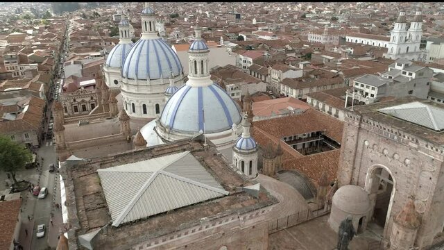 Drone descends the front of New Cathedral in Cuenca, Ecuador. It starts with an aerial view of the famous blue domes, then decends along the front face to the ground.