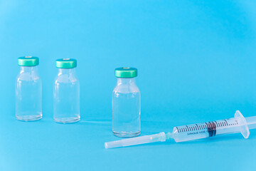 Potential trials stage concept on blue background. Close up Vials with sterile needle syringe. Research and Development, Vaccination.