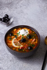 Soup with smoked olives and lemon in a gray plate