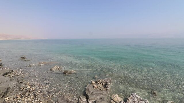 Clear water and natural black mud full of minerals, on a wild beach in the Dead Sea, Israel.