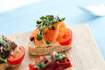 Closeup on salmon and tomato bruschetta with herbs on a wooden board