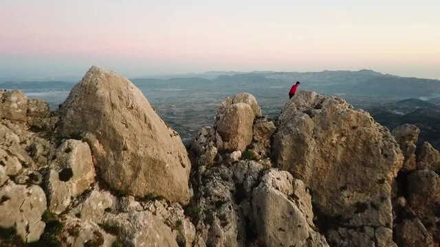 VIDEO OF AN ATHLETE TRAIL RUNNER IN A MOUNTAIN. A PERSON HIKING AT THE TOP OF A MOUNTAIN. RUNNER ON EDGE OF CLIFF. SPORT, OUTDOOR AND VERTIGO. 