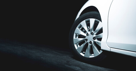 Alloy wheels of the white car are turning on the cement road of parking lot with copy space on the...