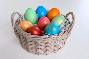 Painted chicken eggs in a wicker basket on a white table. Easter concept Handmade, creativity with children for decoration on easter