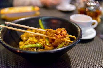 Thai food-Stir fried Noodle, Pad Thai in dark plate with sticks