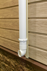 Plastic drain pipe. Building wall with panels. White plastic. Vertical arrangement.