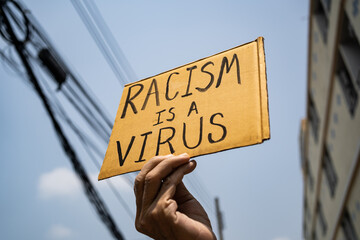 A man holding Racism is a Virus sign