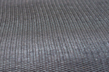 Black synthetic textile furniture upholstery mesh. Background with holes textured pattern.