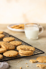 Healthy oatmeal cookies with cereals, seeds and nuts with a cup of milk on concrete background. Diet vegan cookies.