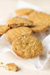 Healthy oatmeal or multigrain cookies with seeds and nuts on baking paper, light concrete background.
