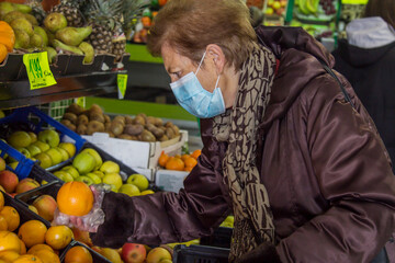 senior woman with medical mask shopping at market fruit stall, new normal concept