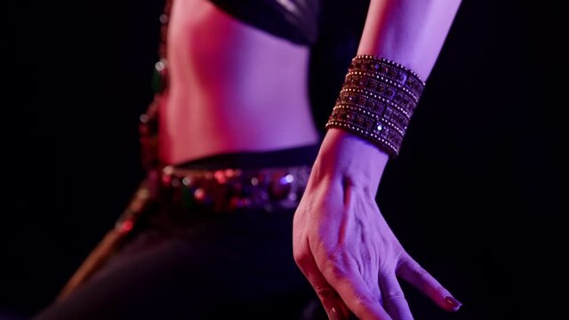traditional belly dance, woman is wearing arabian or indian suit is moving abdomen in darkness
