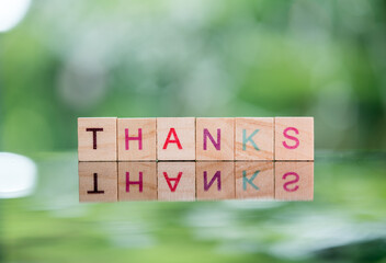 Words concept, THANKS word cube on reflection floor bokeh blur background ,English language learning concept.