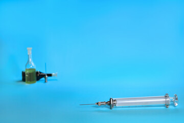 Syringe for vaccination. Behind are ampoules with solution and a replaceable needle. Composition on a blue background