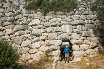 Obraz na płótnie Canvas Hiking the Lycian Way. Man is trekking through doorway of Delikkemer Aqueduct, well-preserved polygonal masonry wall, Outdoor activity in Turkey