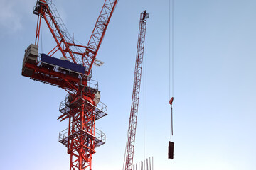 Cranes high-rise, Construction site, On backdrop of blue sky and sunrise morning with copy space, Industrial machine engine and mechanical outdoor workplace, Development land and residential in city.