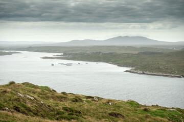Small narrow asphalt road with beautiful unique views, Sky road loop near Clifden town, county Galway, Ireland. Cloudy sky. Irish scenery. Nature landscape. Popular tourist travel destination