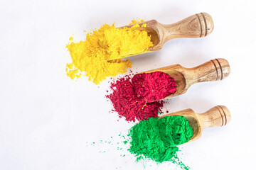Colorful holi powder or gulal in wooden scoop on white isolated background.