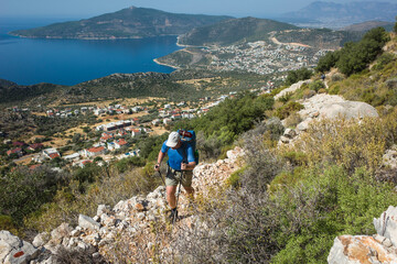 Hiking Lycian way. Man is trekking on stony path high above Mediterranean sea coast on Lycian Way trail near Kalkan, Outdoor activity in Turkey