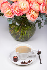 A cap of coffe with sweet and coffee beans near the vase with flowers