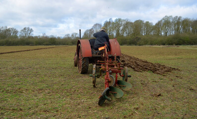 Vintage red International 1930's  tractor ploughing field. 