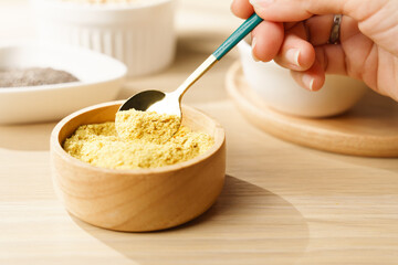 Nutritional yeast flakes in wooden bowl a great source of vitamins and minerals for vegan and...