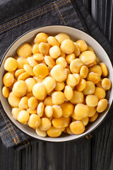 Pickled lupine beans close-up in a bowl on the table. Vertical top view from above