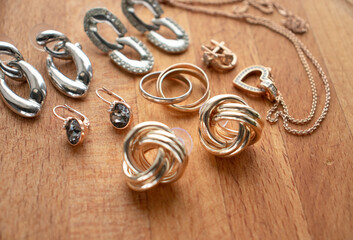 costume jewelry, jewelry made of gold and silver, lie on a wooden surface. Women's day, stylish...