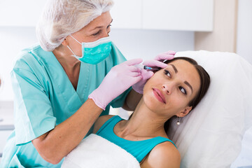 Fototapeta premium Young woman getting injection for facial correction procedure in esthetic clinic