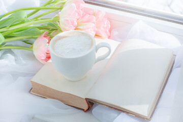  cup of coffee an old book and a bouquet of tulips on the window still life