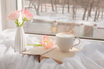 still life a vase with tulips and an old book on the window
