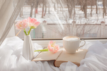 still life a vase with tulips and an old book on the window