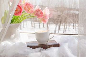 still life a vase with tulips and an old book on the window