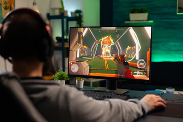 Pro gamer playing virtual shooter game for online competition using professional headphones. Online...
